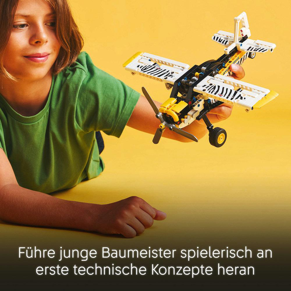 Ein Kind mit einem Lego-Flugzeugmodell, auf gelbem Hintergrund.