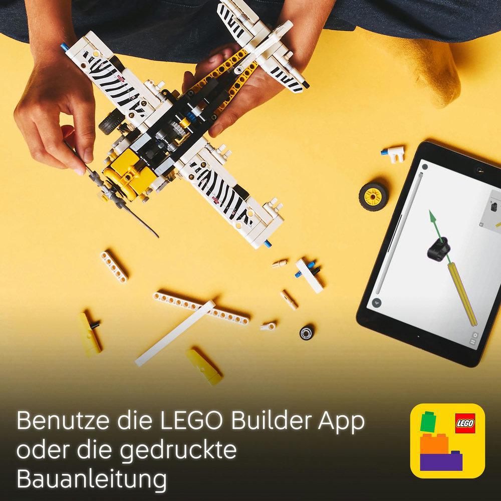 Ein Kind baut ein Lego-Flugzeug mit verstreuten Teilen zusammen, geführt von einem Tablet mit Anweisungen.