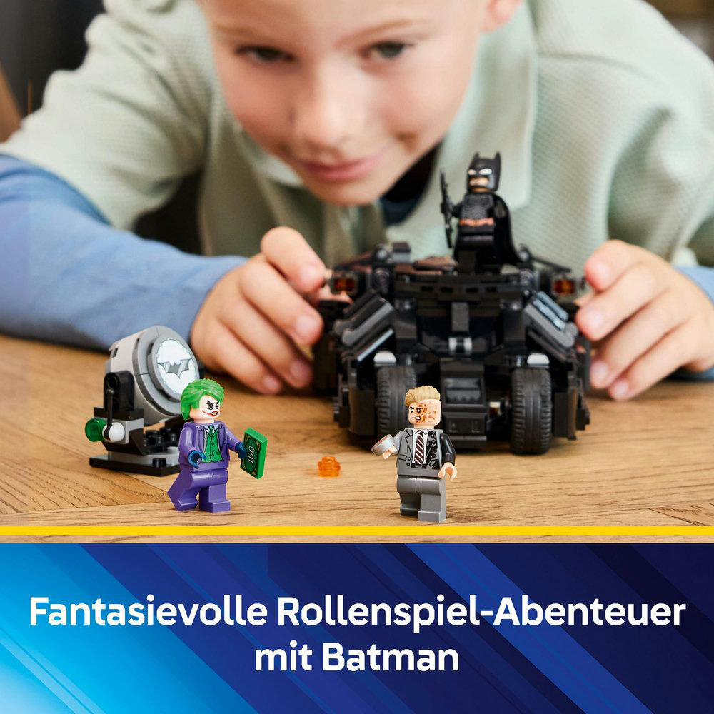 Ein Kind baut ein Lego-Set zusammen, das Batman, den Joker und ein Tumbler-Fahrzeug zeigt.