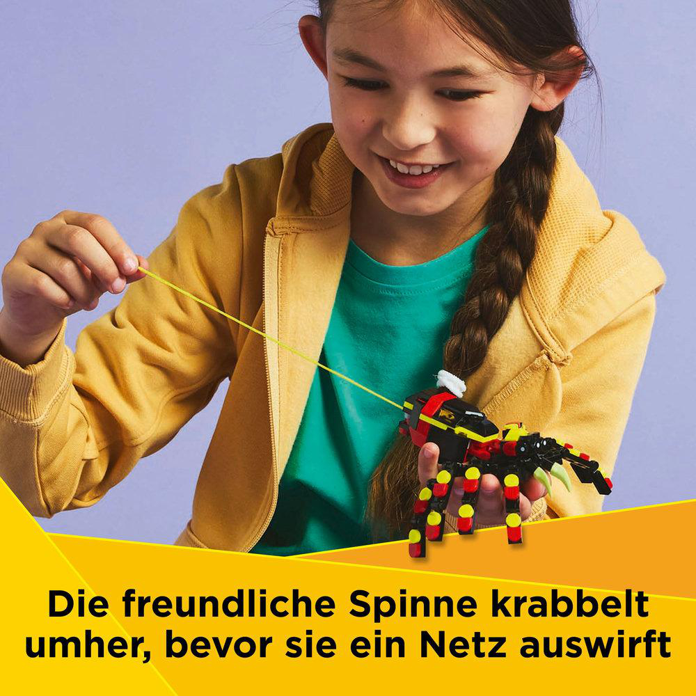 Ein Mädchen lächelt eine Lego-Spinne mit gelben und schwarzen Segmenten und einem gelben Faden an.