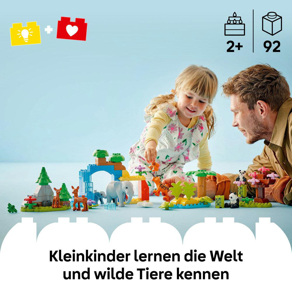 Kind und Mann spielen mit Lego-Spielzeug in einem Raum. Spielzeug umfasst Tiere und Strukturen.