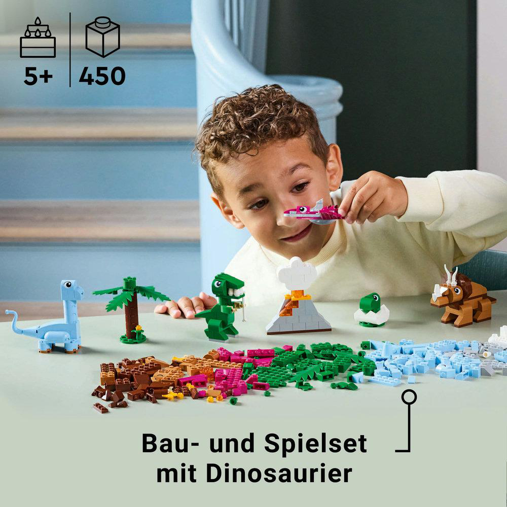 Ein Kind spielt mit Lego-Dinosaurier-Modellen und -Blöcken. Mehrere Dinosaurier und ein Vulkan sind sichtbar.