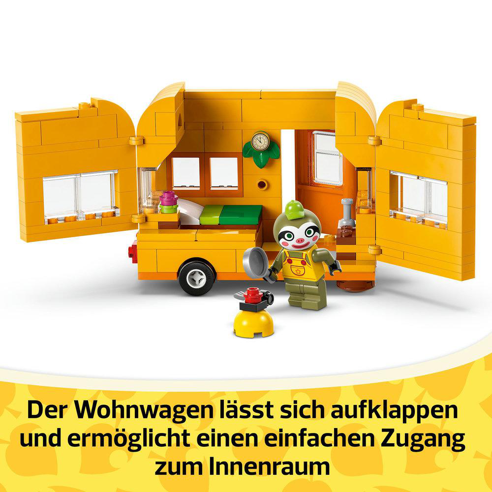 Ein Lego Wohnwagen-Set. Der Wohnwagen hat offene Türen, eine Figur hält eine Bratpfanne und einen Herd.