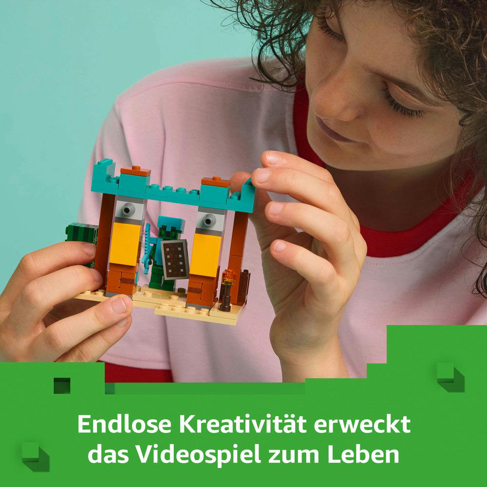 Ein Kind hält ein Lego Minecraft-Bauwerk. Das Set zeigt eine Szene mit Blöcken, Figuren und einem Tor.
