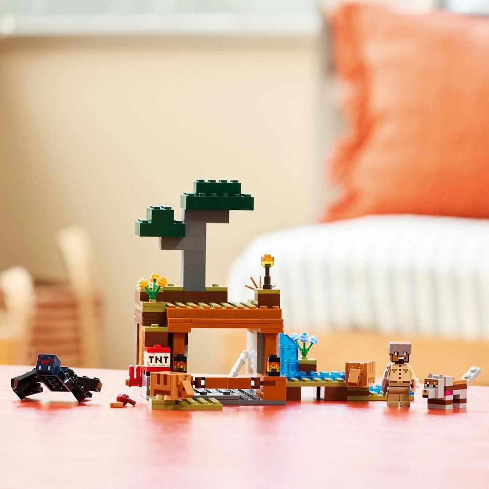 Lego-Set mit braunen und grünen Strukturen, Figuren und einer schwarzen und roten Kreatur.