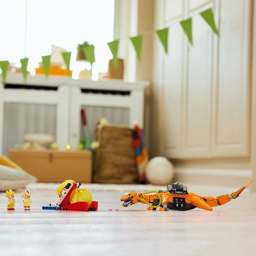 Ein Lego-Set mit zwei Minifiguren und einem orangefarbenen Dinosaurier auf Holzboden.