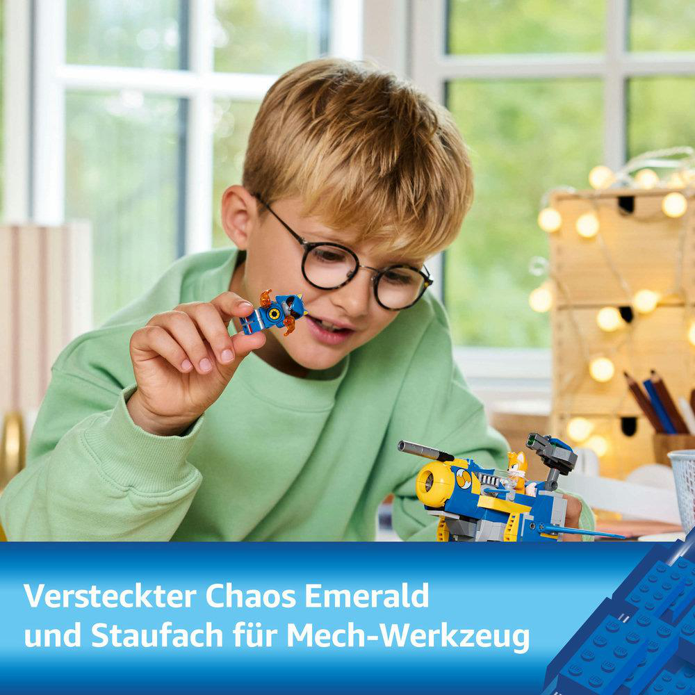 Ein Junge spielt mit Lego. Blauer und gelber Lego-Roboter und ein blauer Hintergrund.