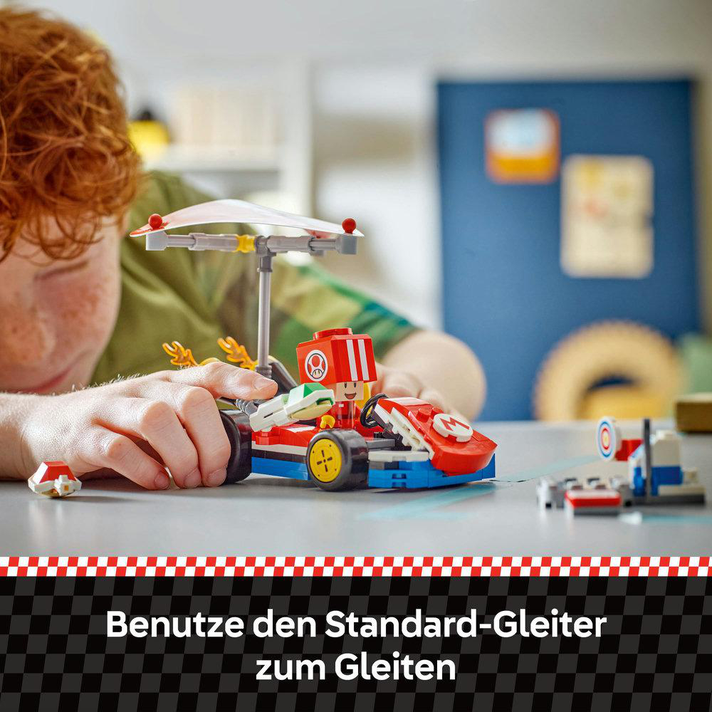 Ein Kind spielt mit einem Lego Mario Kart Modell auf karierter Oberfläche.