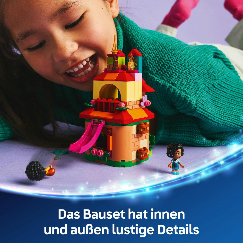 Ein Kind lächelt bei einem Lego-Set mit einem bunten Gebäude mit Rutsche.