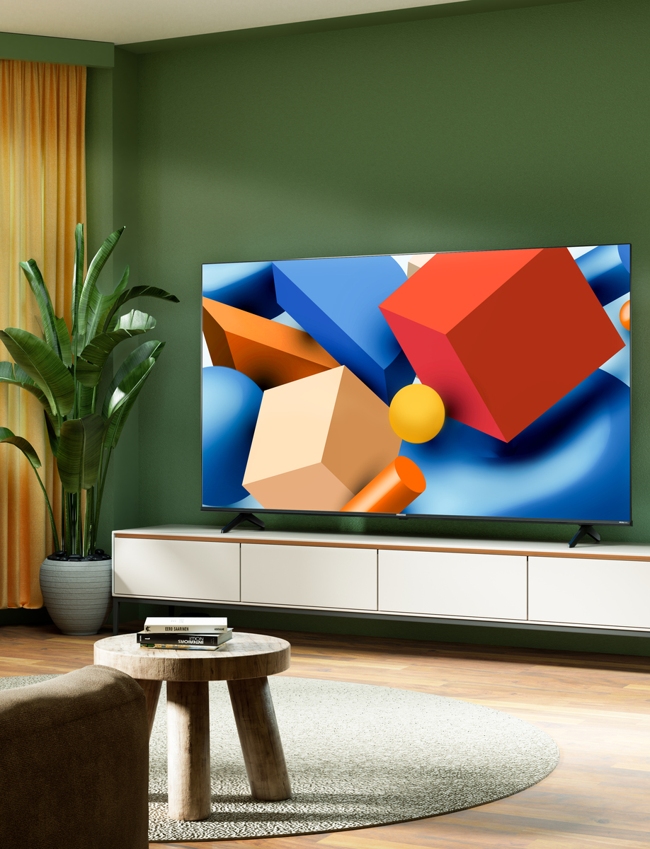 Duży telewizor wyświetla kolorowe geometryczne kształty na białej szafce w zielonym pokoju.