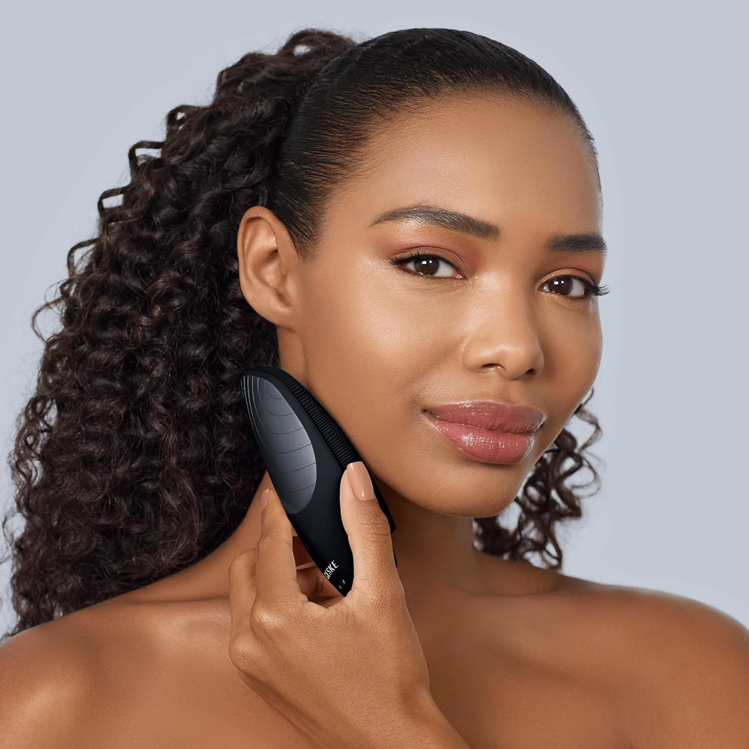Una mujer con cabello rizado oscuro usando un dispositivo facial negro.