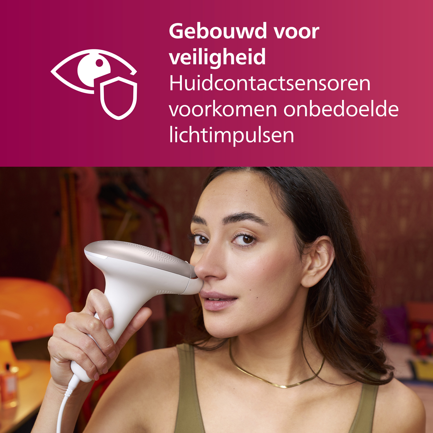 Een vrouw houdt een ontharingsapparaat bij haar gezicht. Ze draagt een groene top. De achtergrond is een kamer.