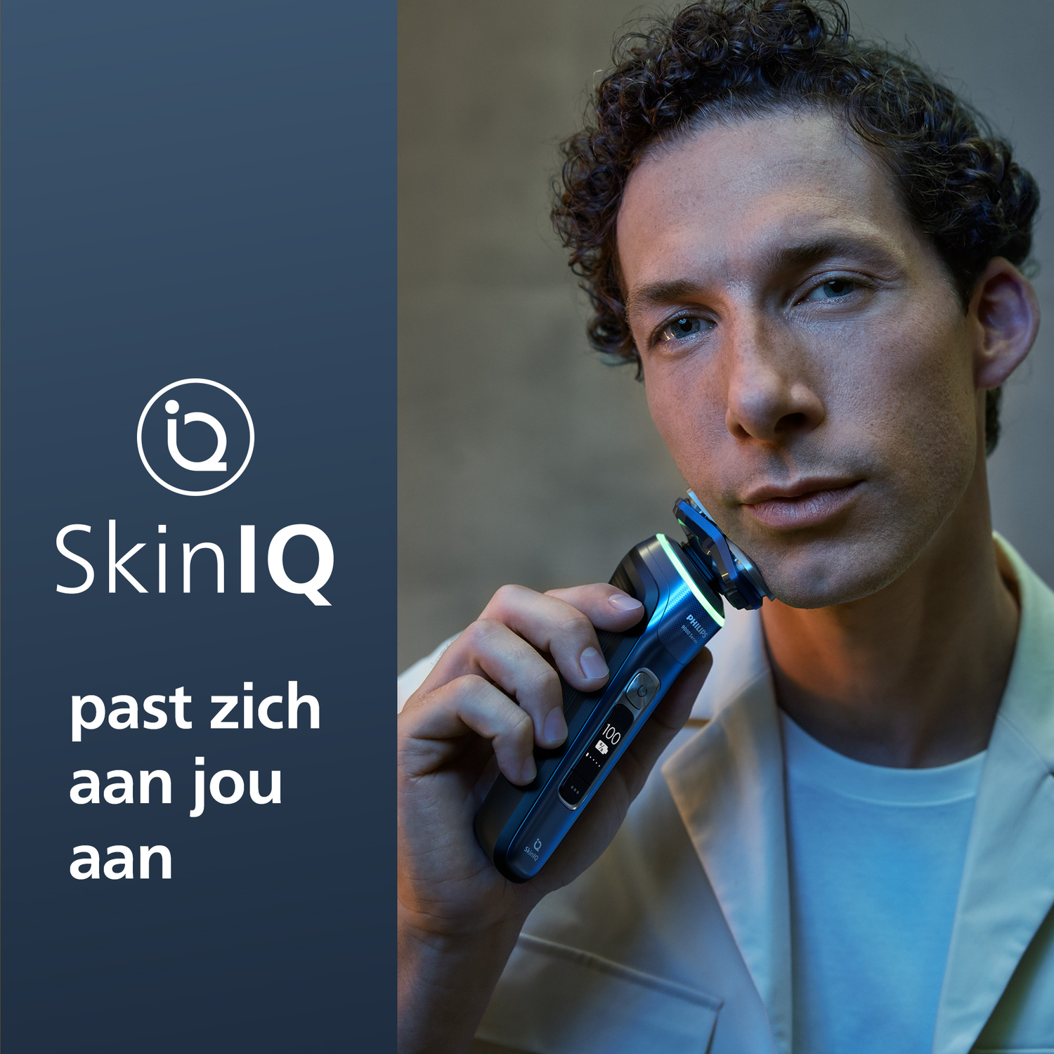 Man shaves with a black and silver electric shaver. Text: SkinIQ adjusts to you.
