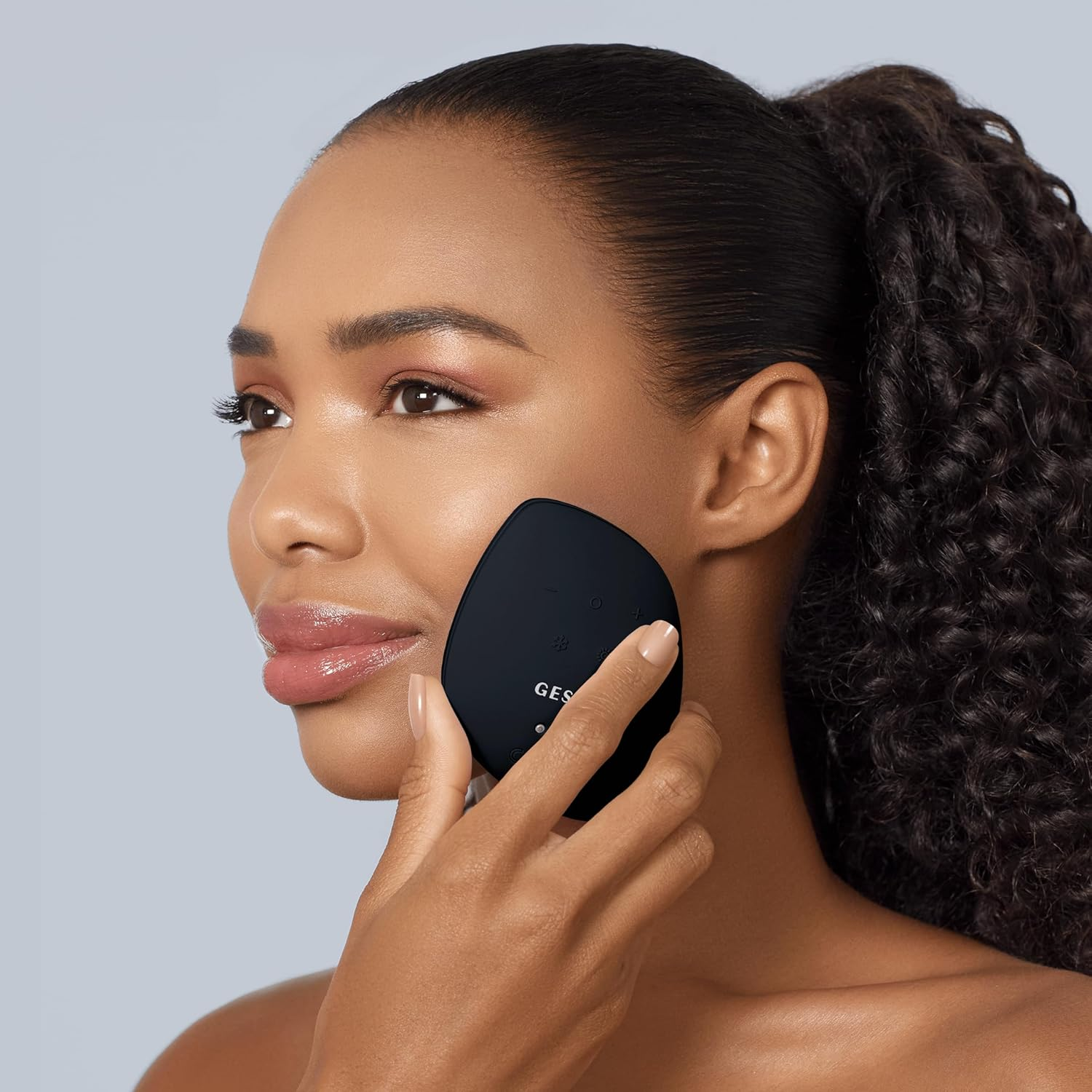 Mujer usa dispositivo facial negro en mejilla, mirando hacia otro lado.