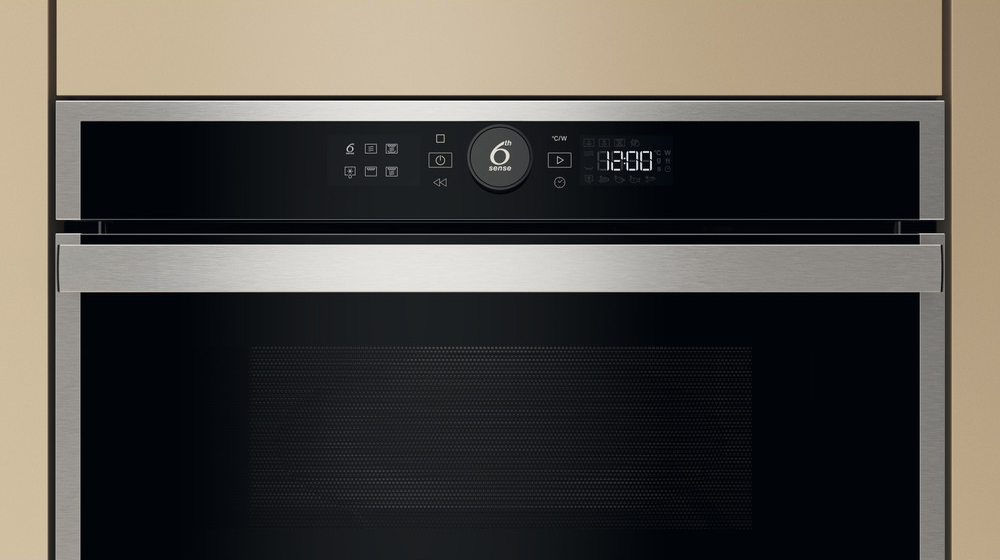 Közelkép egy mikrohullámú sütő vezérlőpaneljéről, ami az időt, gombokat és a Whirlpool logót mutatja. Bézs keret.