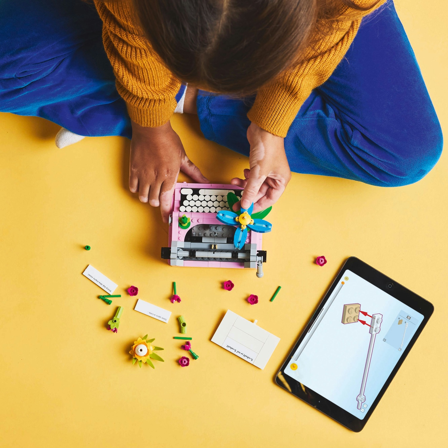 Un bambino che costruisce una macchina da scrivere Lego con un tablet che mostra le istruzioni.