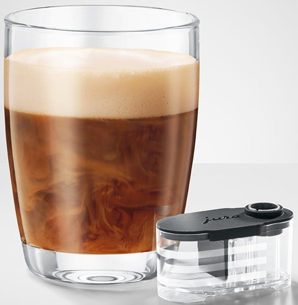 Ein Glas Kaffee mit Schaum, daneben ein klarer Behälter. Der Kaffee hat Milchwirbel. Weißer Hintergrund.