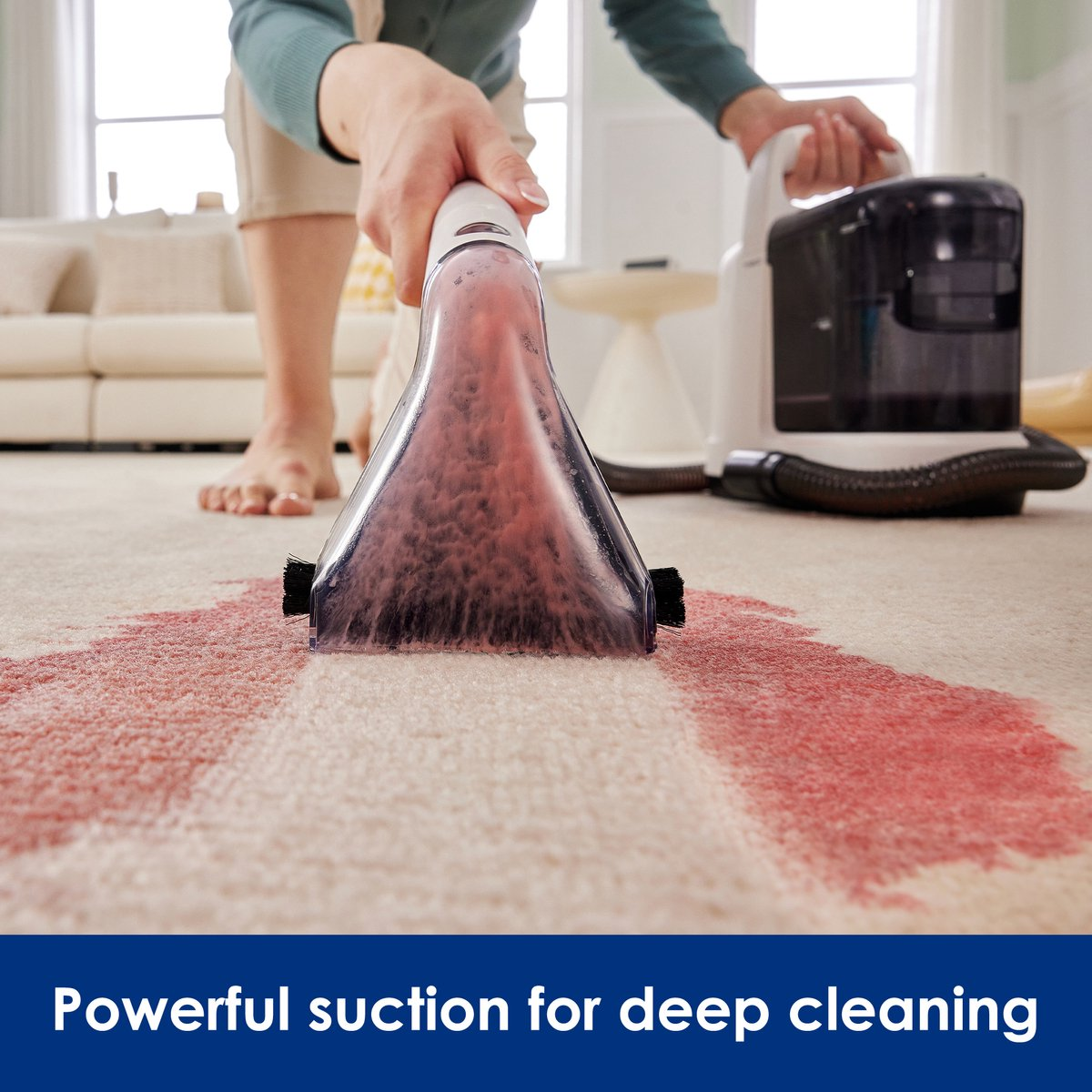Personne nettoyant une tache rouge sur un tapis beige avec un nettoyeur de tapis.