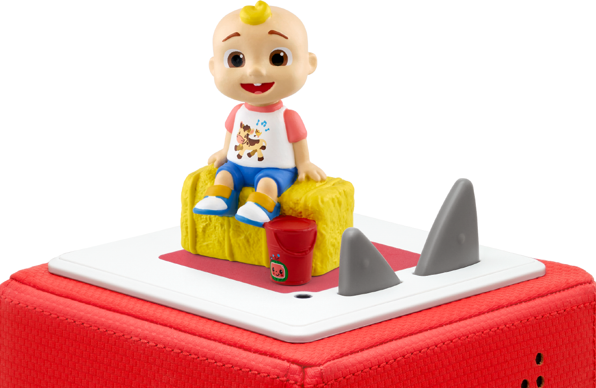 Eine Spielfigur eines Kindes sitzt auf Heu. Ein roter Eimer und Haifischflossen befinden sich auf einer weißen Oberfläche, auf einem roten Würfel.