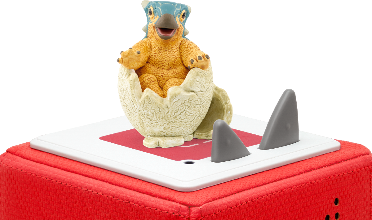 Ein Dinosaurier-Spielzeug, das aus einem Ei schlüpft, auf einer rot-weißen Oberfläche mit zwei grauen Flossen.