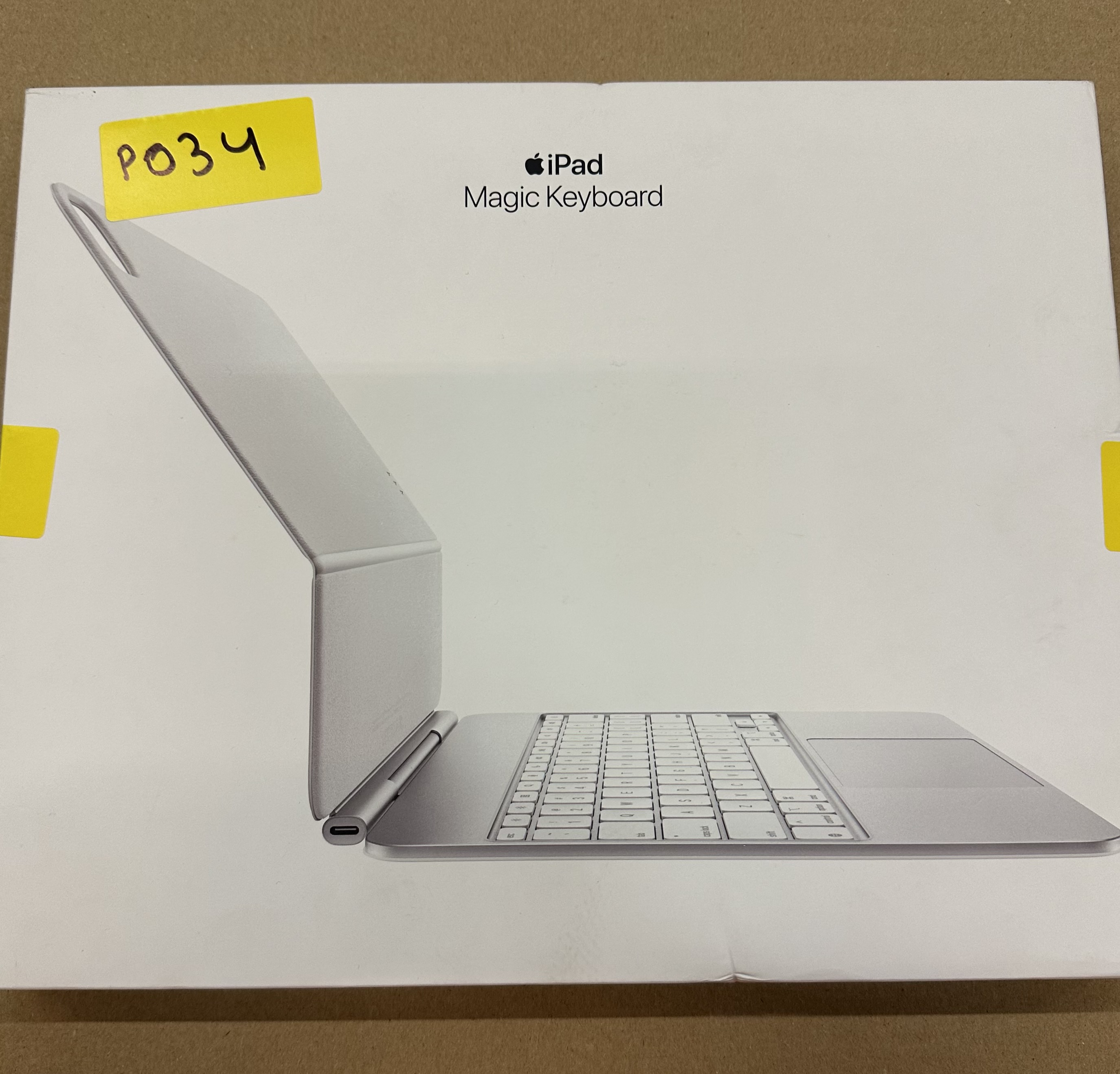 Pudełko Magic Keyboard do iPada. Klawiatura jest otwarta, na pudełku żółta naklejka.