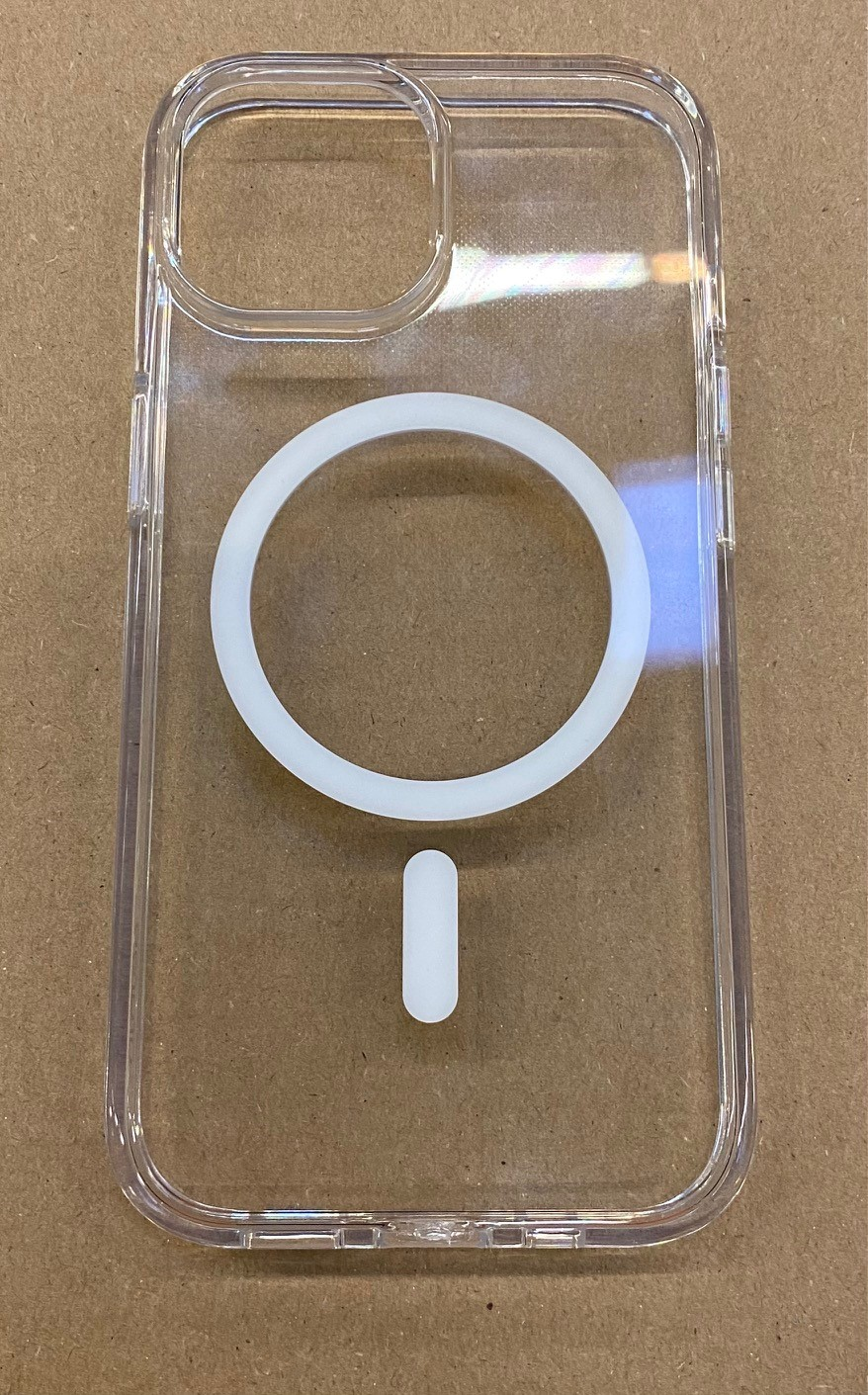 Przezroczyste etui na telefon z pierścieniem MagSafe i pionowym paskiem, na brązowej powierzchni.