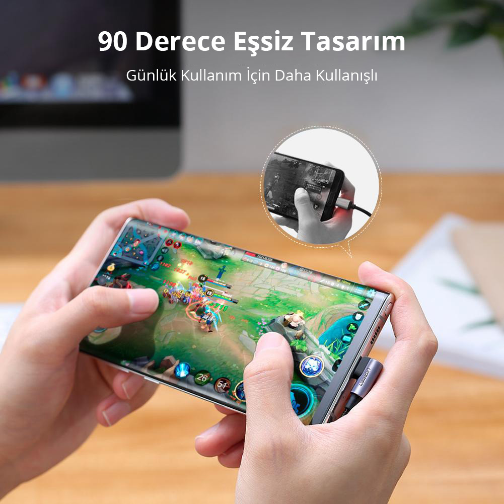 Açılı şarj kablosu bağlı olan bir oyun oynayan bir telefonu tutan eller.