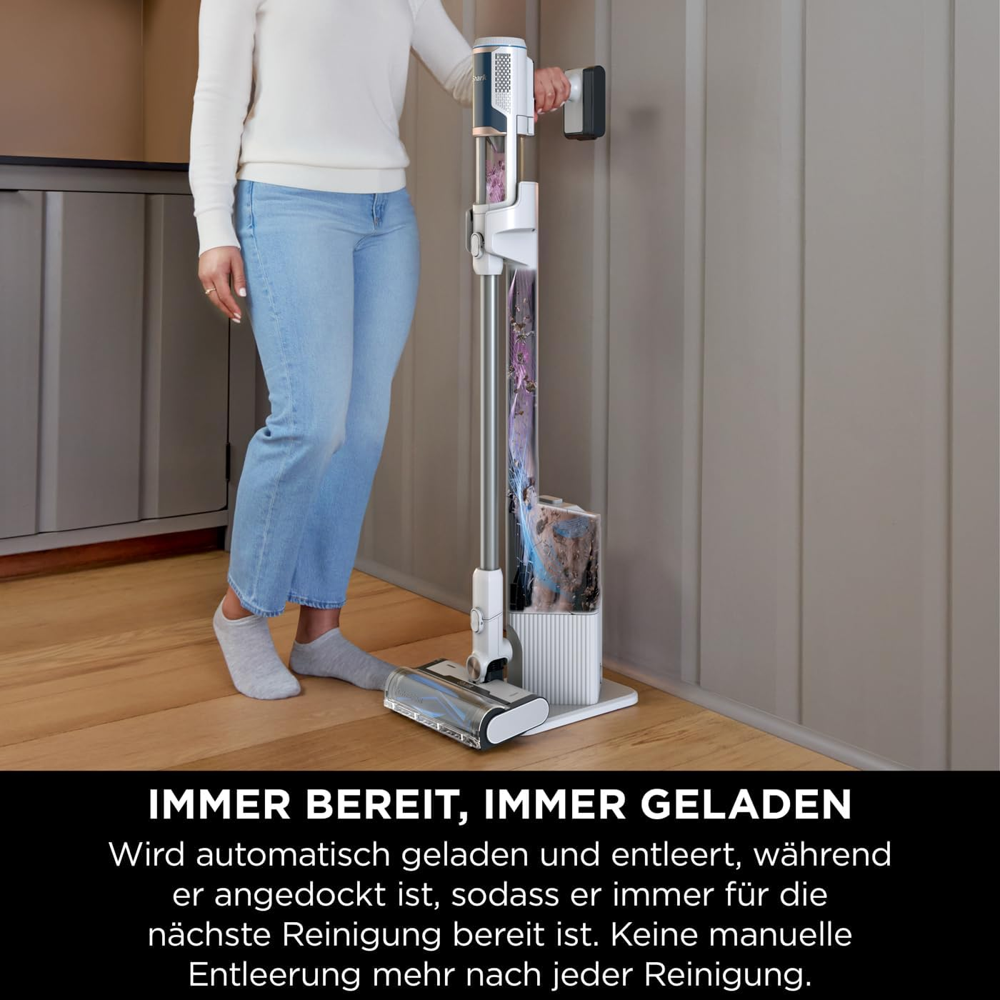 Eine Person mit Staubsauger steht neben einer Ladestation.
