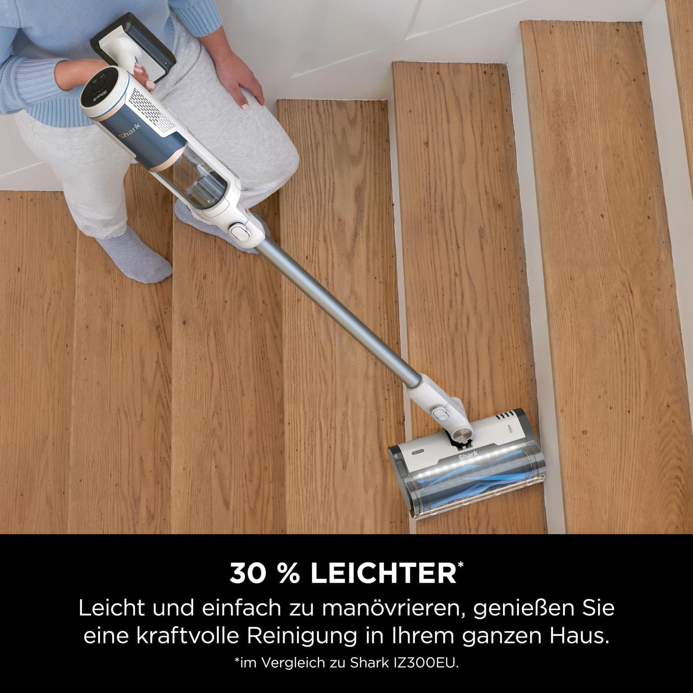Eine Person saugt Holztreppen. Ein Handstaubsauger ist sichtbar.