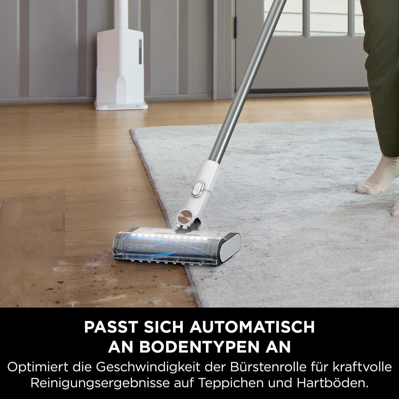 Ein Staubsauger mit Bürstenkopf reinigt einen Teppich mit dem Text 'POWERFINS'.