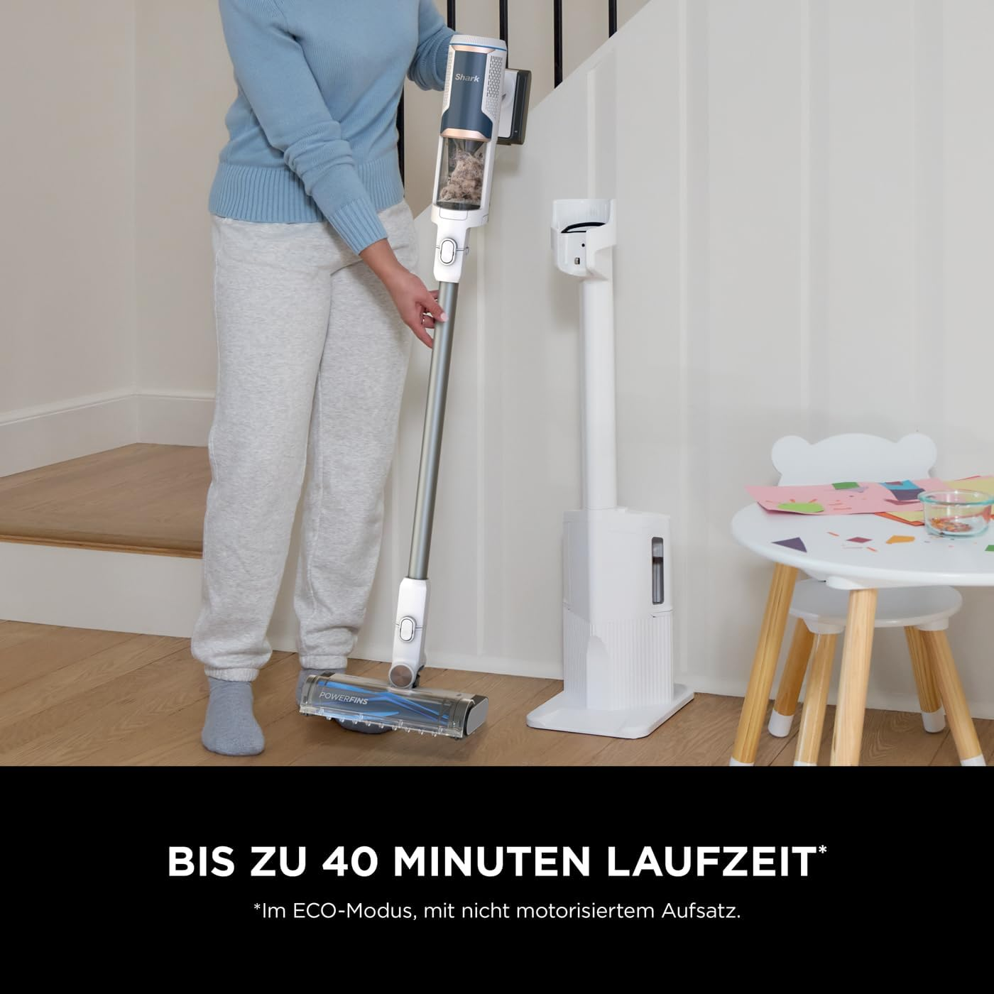 Frau, die in der Nähe eines weißen Ständers und Tisches staubsaugt.