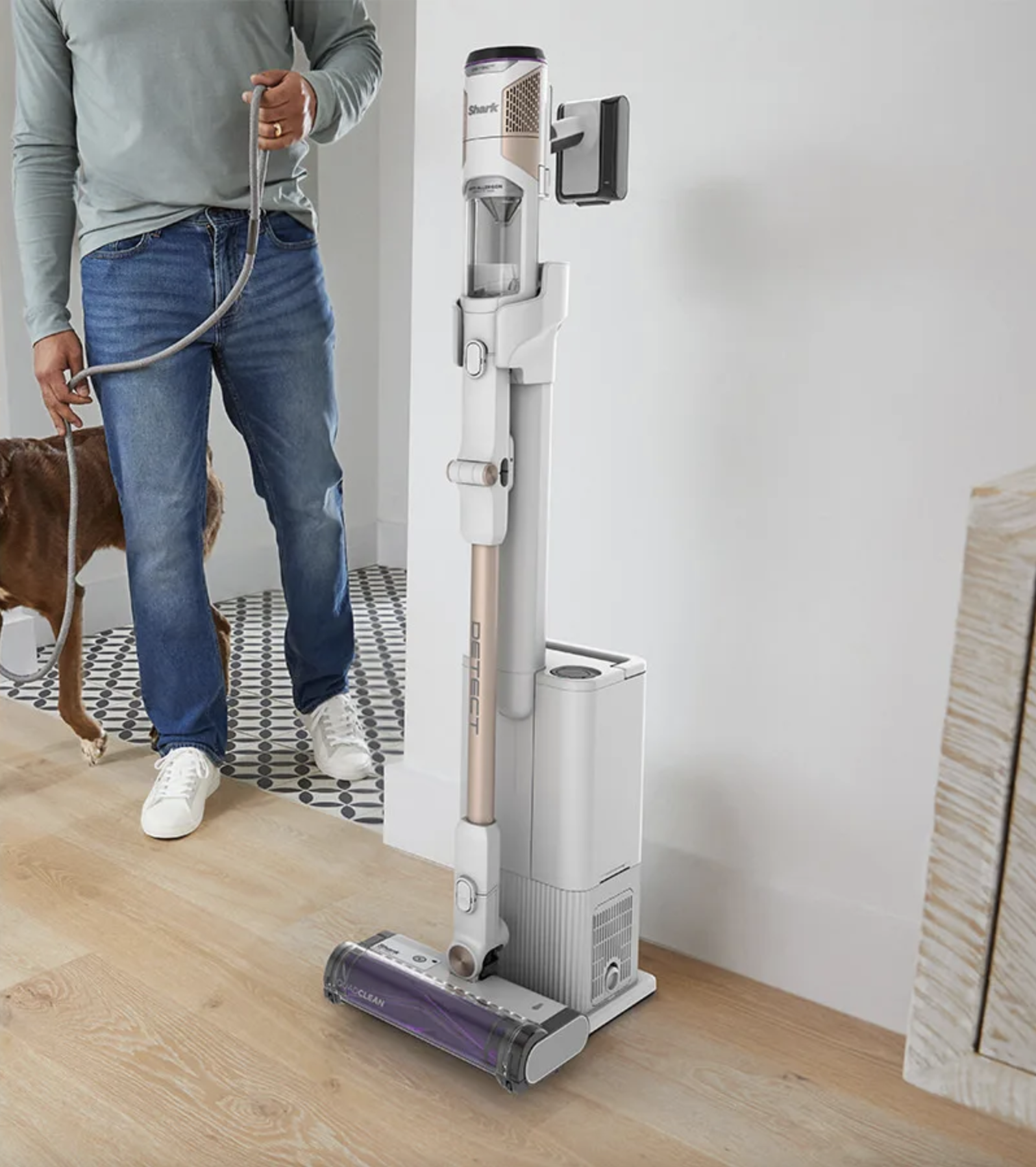 Un homme tenant une laisse se tient à côté d'un aspirateur. L'aspirateur est ancré au mur.