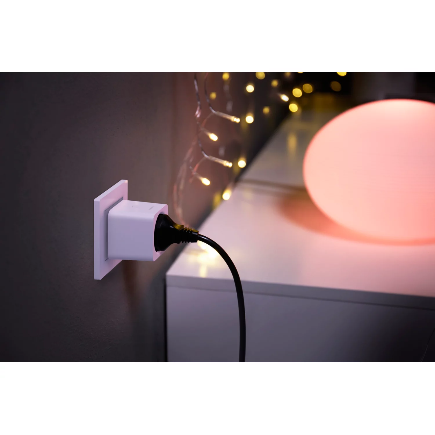 Een slimme stekker aangesloten op een stopcontact, met een zwarte kabel en een roze licht.
