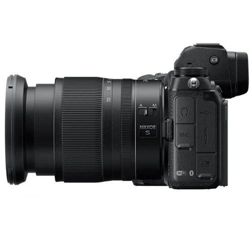 Siyah kamera ve lens takılı, yan görünüm. Beyaz arka plan.
