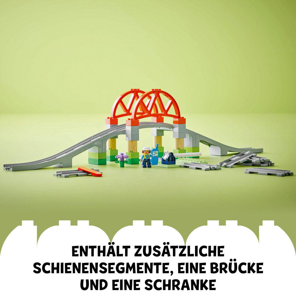 Ein Spielzeugbrückenset mit Brücke, Schienen, Figuren und Text unten.