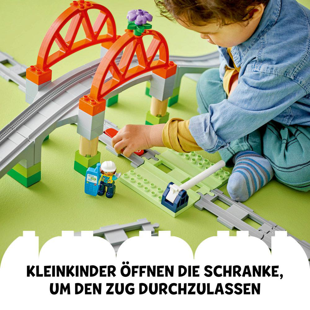 Kind spielt mit Zugset, orangefarbene Brücke, Nahaufnahme.