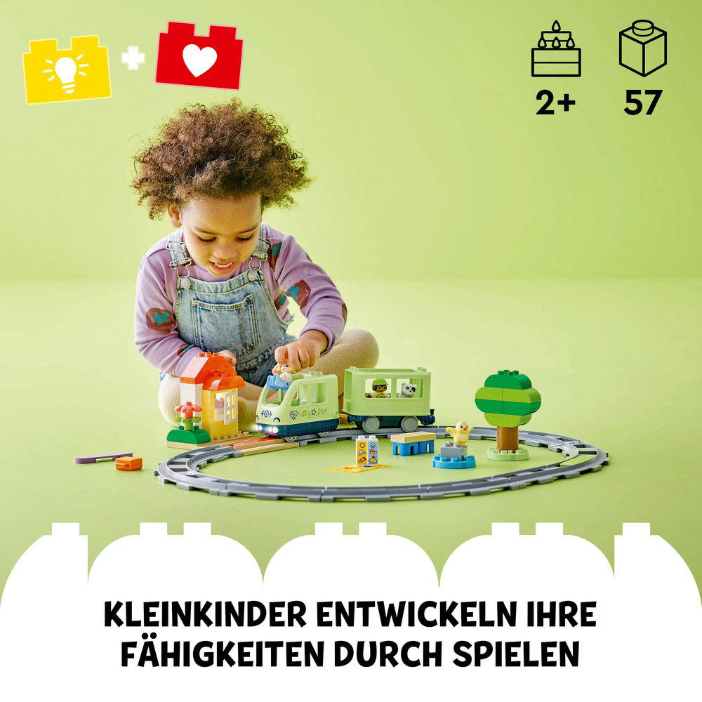 Ein junges Kind spielt mit einem Spielzeugeisenbahn-Set mit bunten Teilen.