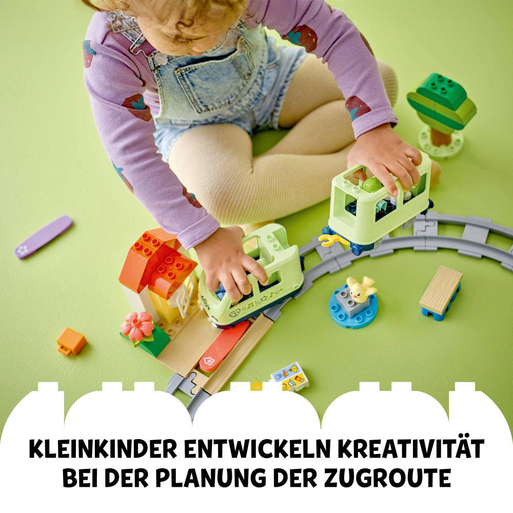 Ein Kind spielt mit einem Spielzeug-Zug-Set und arrangiert die Schienen.