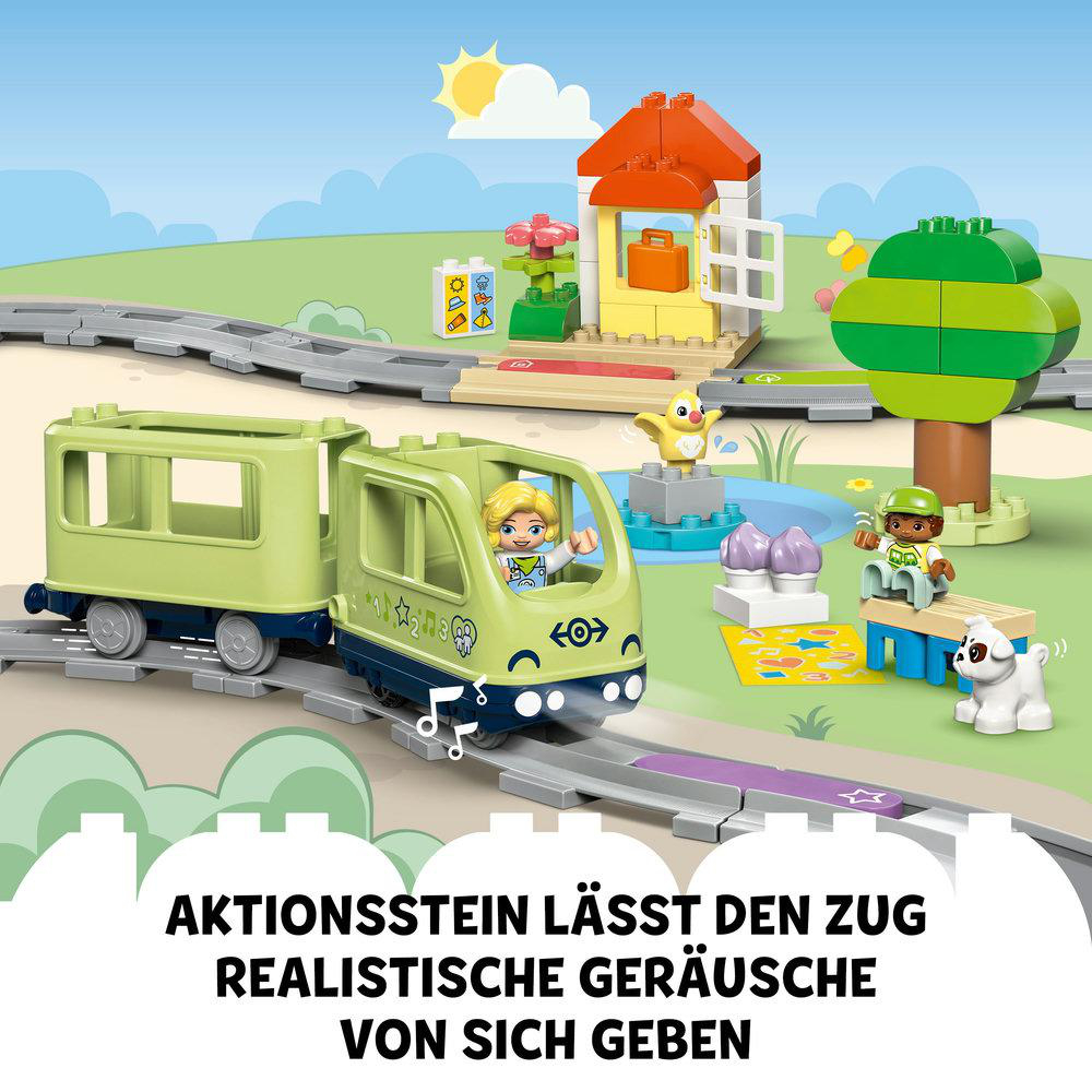 Ein grünes Spielzeug-Zug mit einem blonden Mädchen darin und Landschaft.