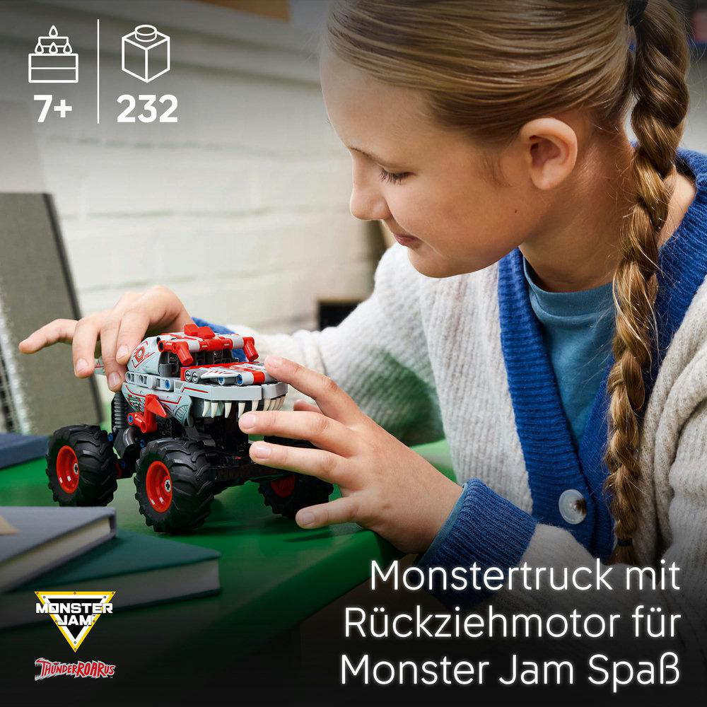 Ein Mädchen spielt mit einem Spielzeug-Monstertruck auf einer grünen Oberfläche.
