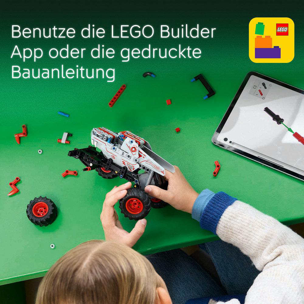 Ein Kind baut einen Lego-Truck auf einer grünen Oberfläche zusammen, mit Tablet und Teilen.