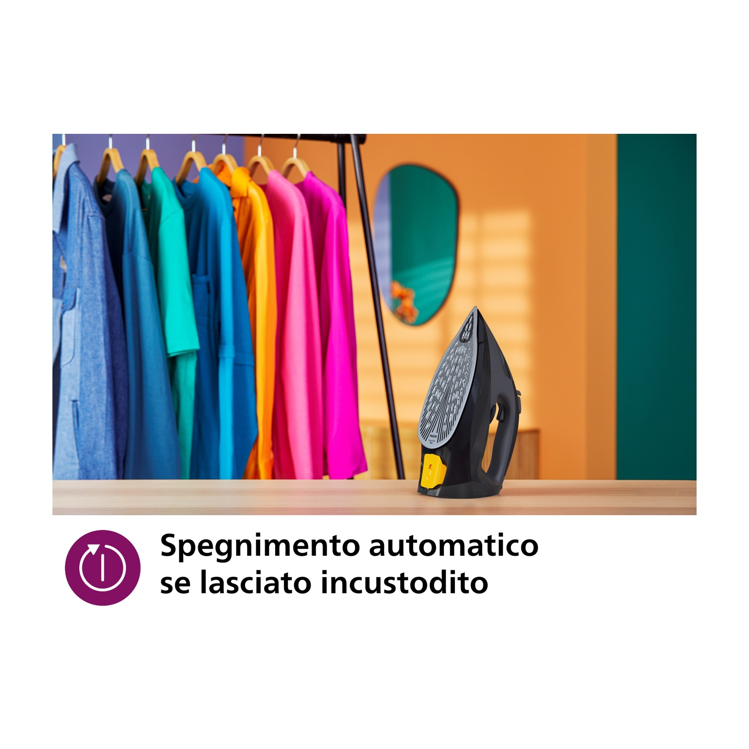 Un ferro da stiro su un tavolo con vestiti colorati appesi. Il ferro è nero e i vestiti sono vivaci.