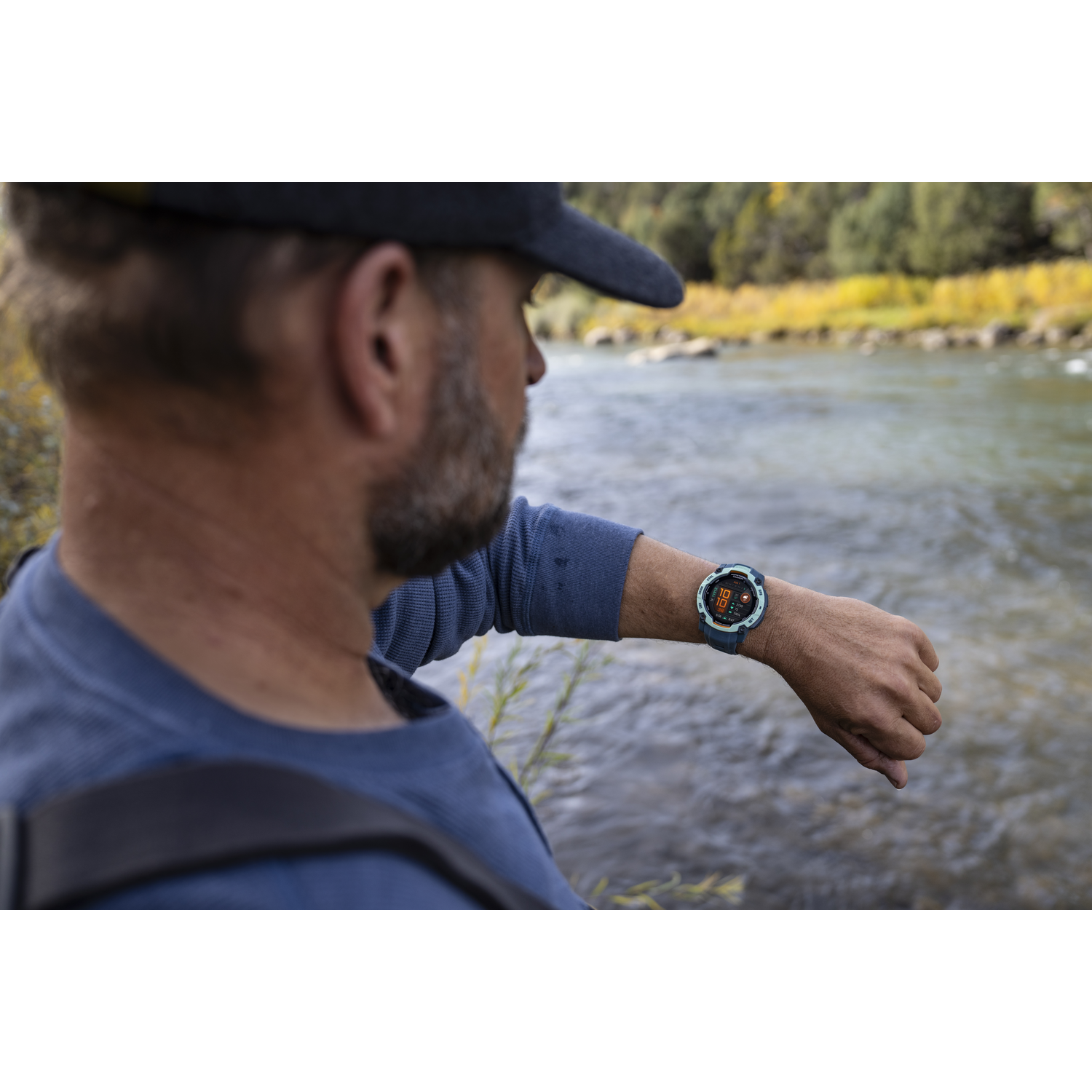 Man met smartwatch, staat bij een rivier.