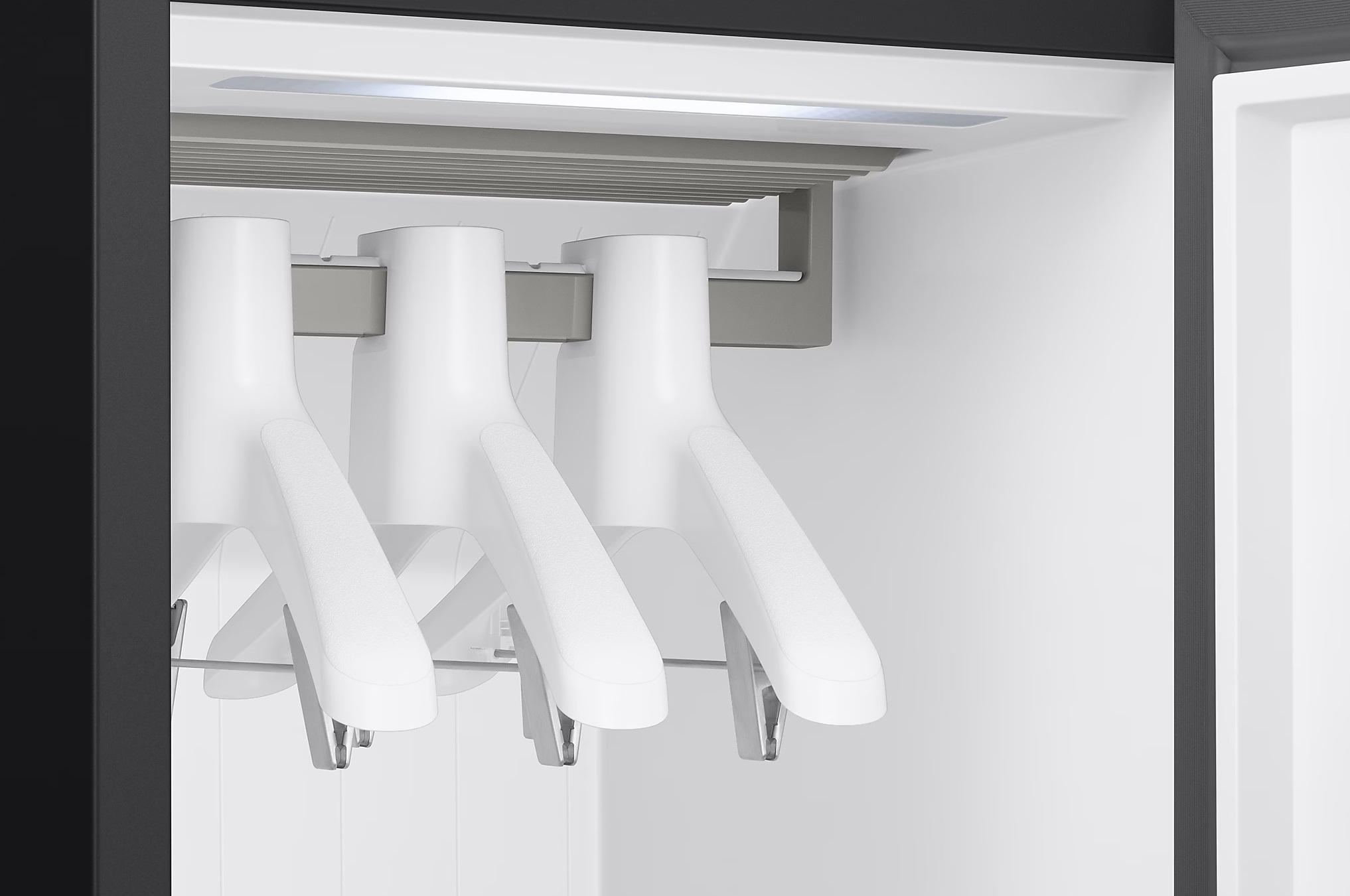 Zbliżenie białych wieszaków w czarnej szafie.