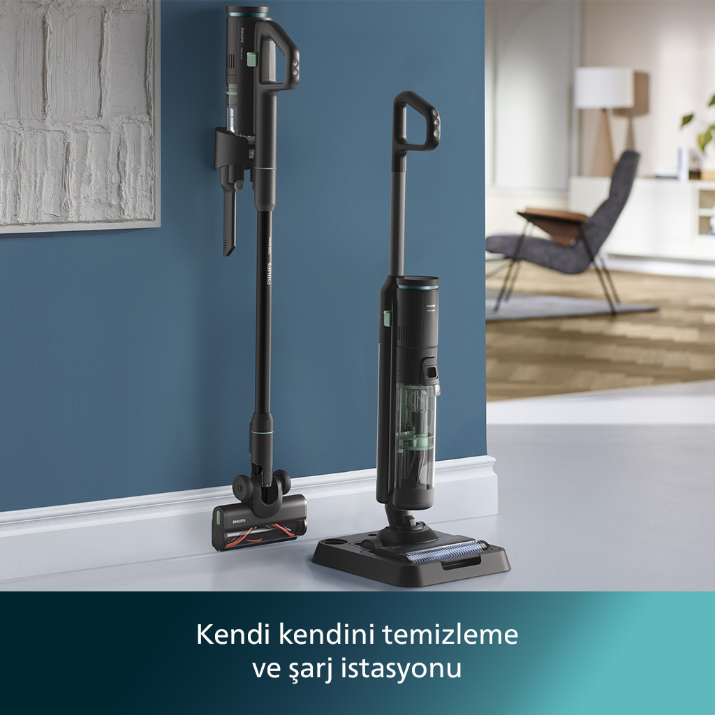 İki siyah elektrikli süpürge, biri duvarda, biri yerde, mavi duvar arka planı.