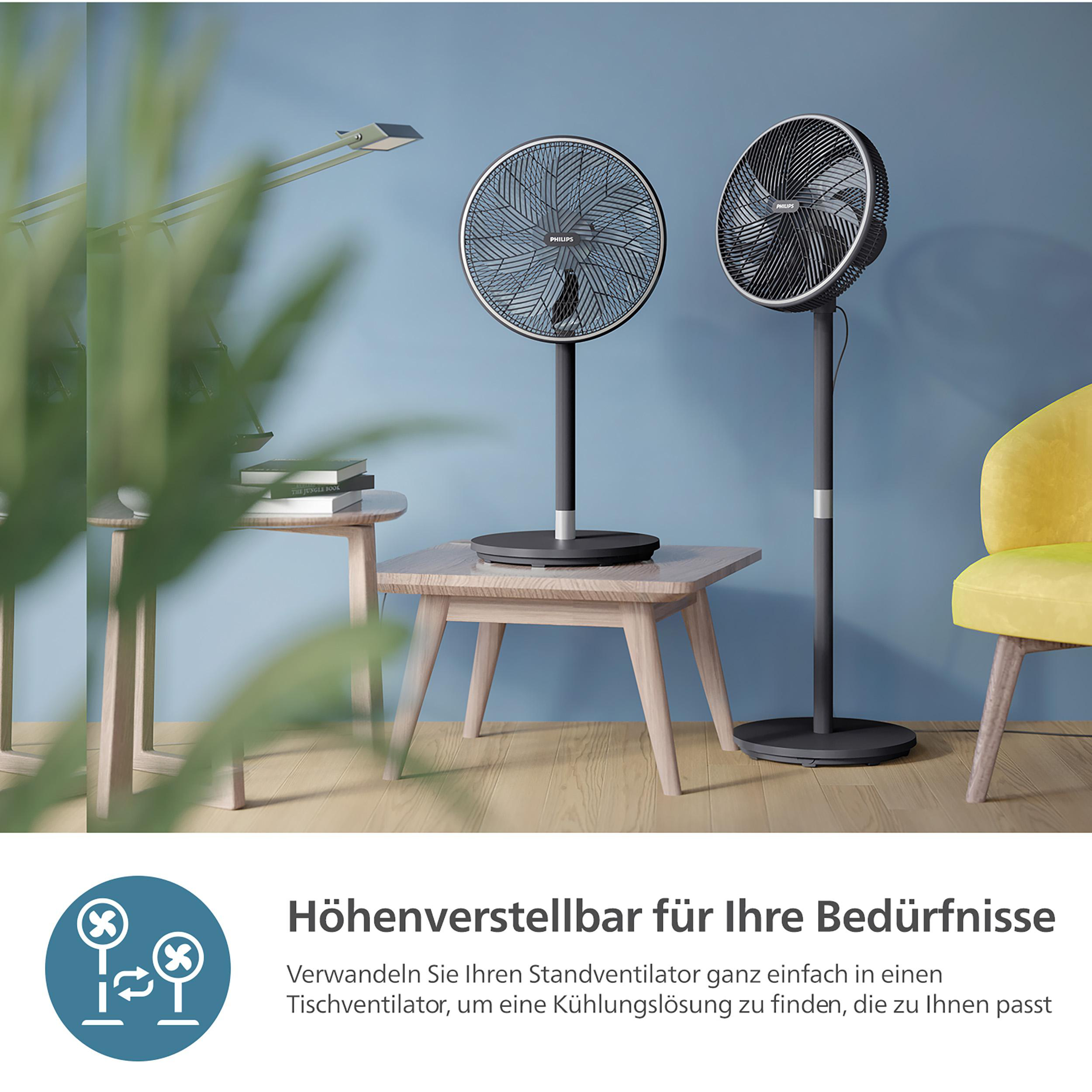 Zwei schwarze Philips-Standventilatoren auf Holztischen, mit blauer Wand und gelbem Stuhl.
