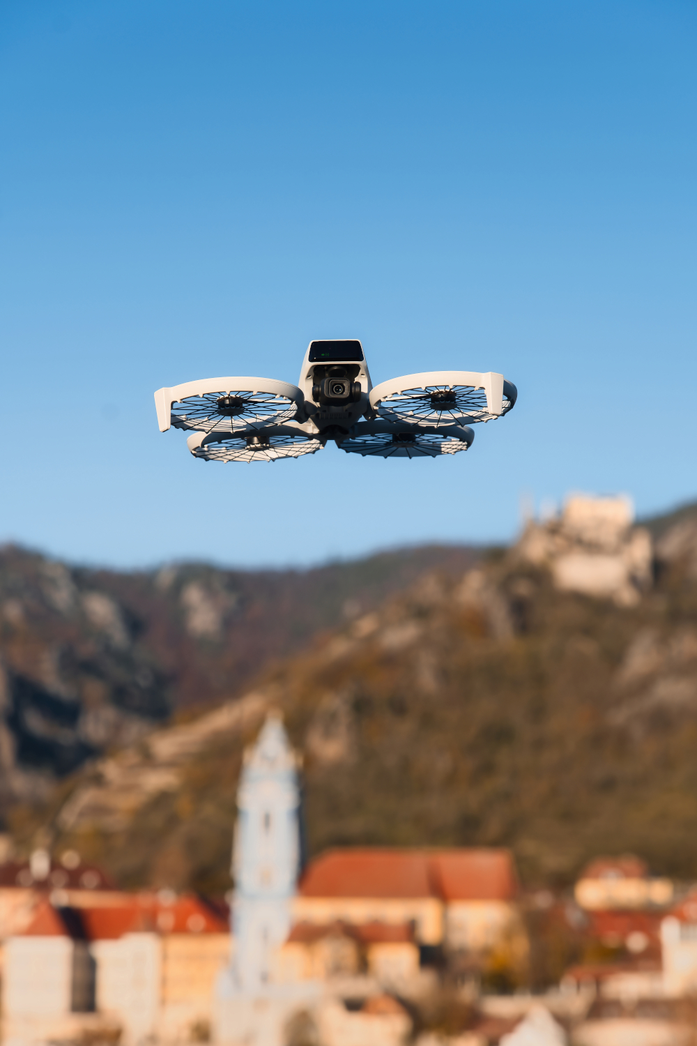 Dron w locie, z miastem i górami w tle.