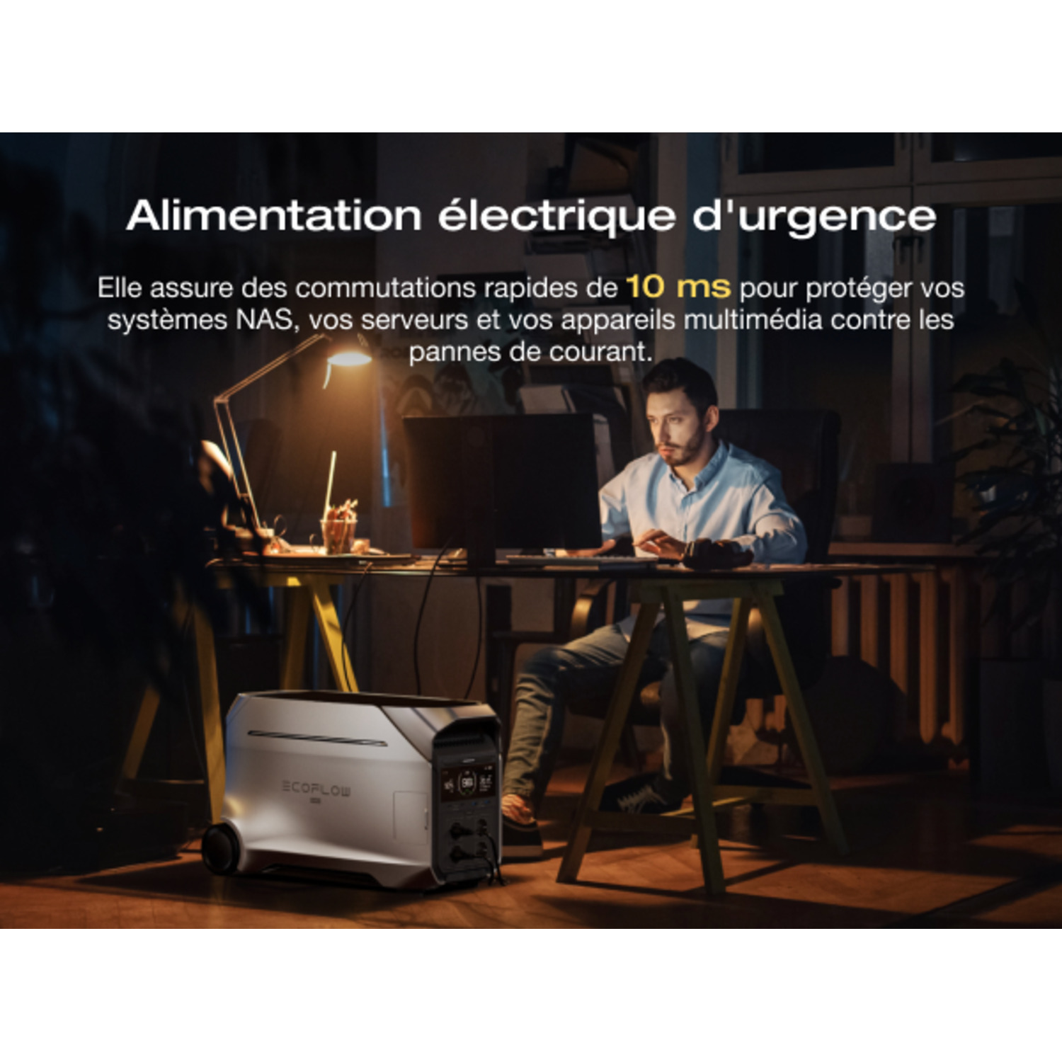 Un homme travaillant à un bureau avec une centrale électrique à côté de lui, dans une pièce sombre.