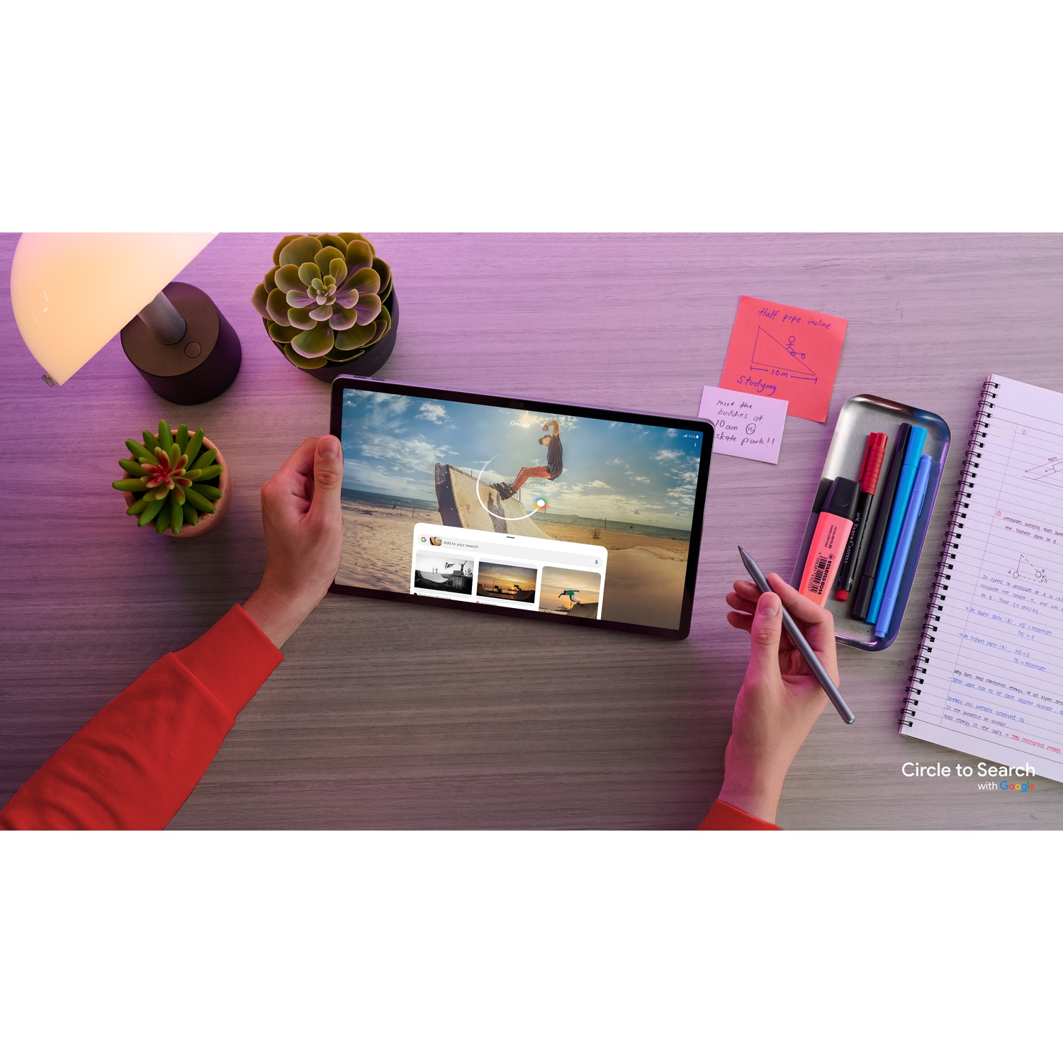 Mani che tengono un tablet con immagini di surf, penna e oggetti da scrivania.