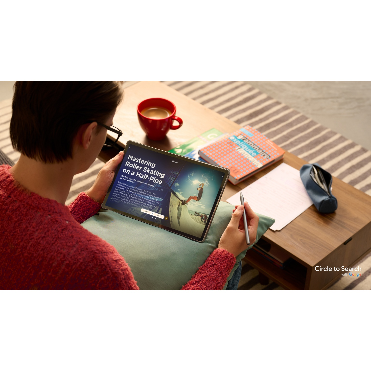 Persona che tiene in mano un tablet con info sul pattinaggio, penna e oggetti da scrivania.